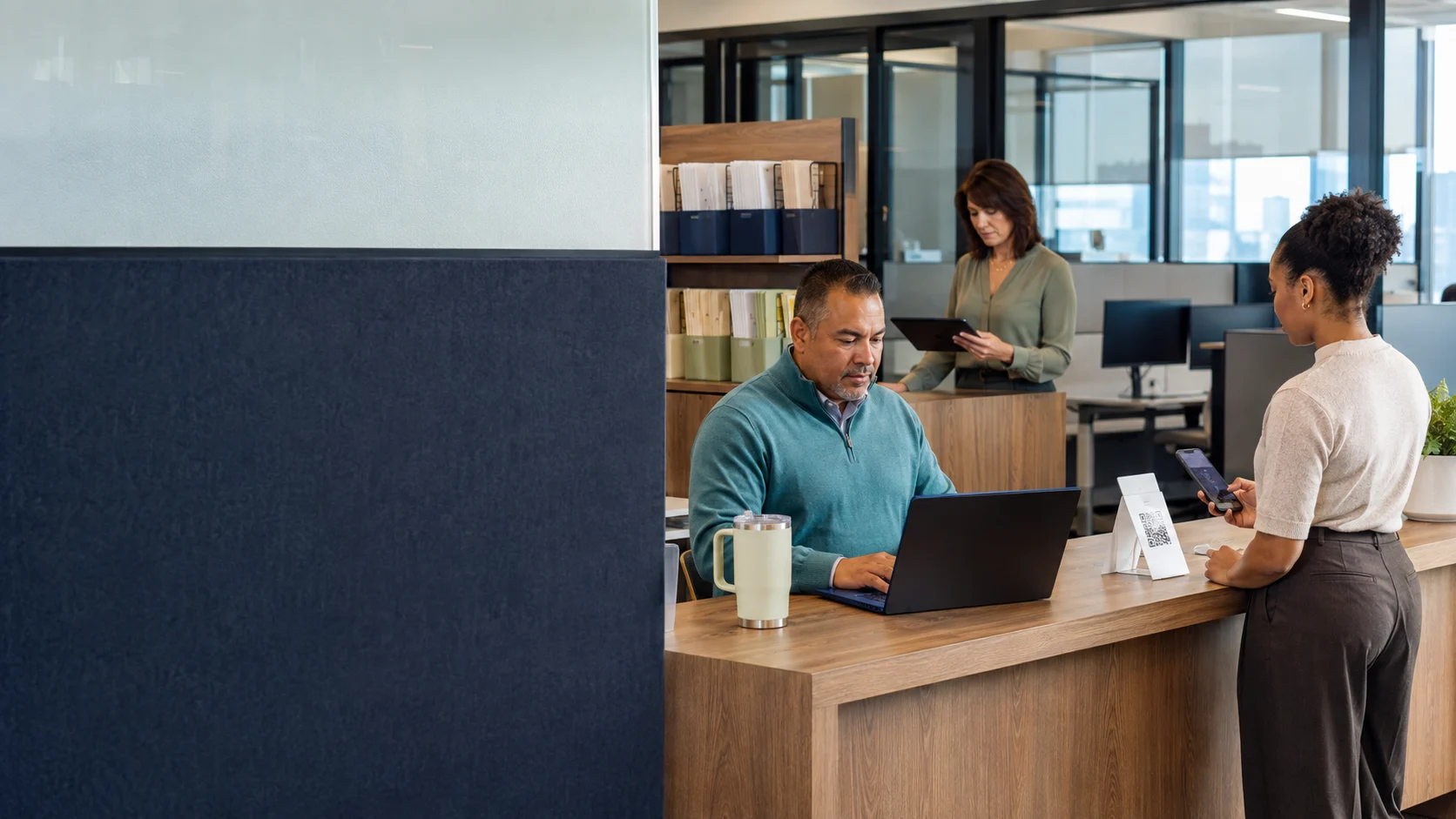 Employees completing benefits enrollment while an HR coordinator manages the process in a professional office.