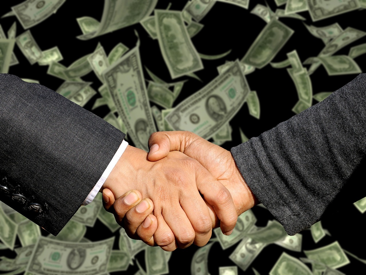 Business professionals shaking hands on a PEO partnership agreement in a modern office